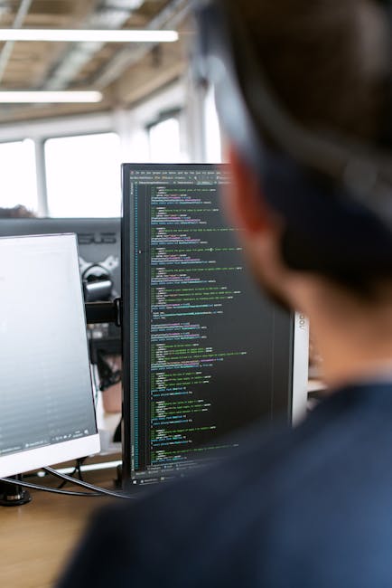 The image depicts a close-up view of a computer screen displaying lines of programming code with syntax highlighting in various colors such as green, blue, purple, and white, reflecting a coding envir